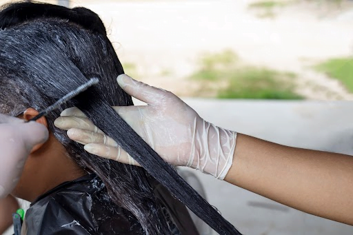 harmful chemical hair relaxer products being distributed on woman's hair.