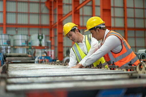 construction workers with hard hats using heavy machinery with injury in factory