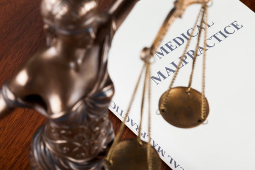 scale of justice on top of medical malpractice forms with delayed diagnosis