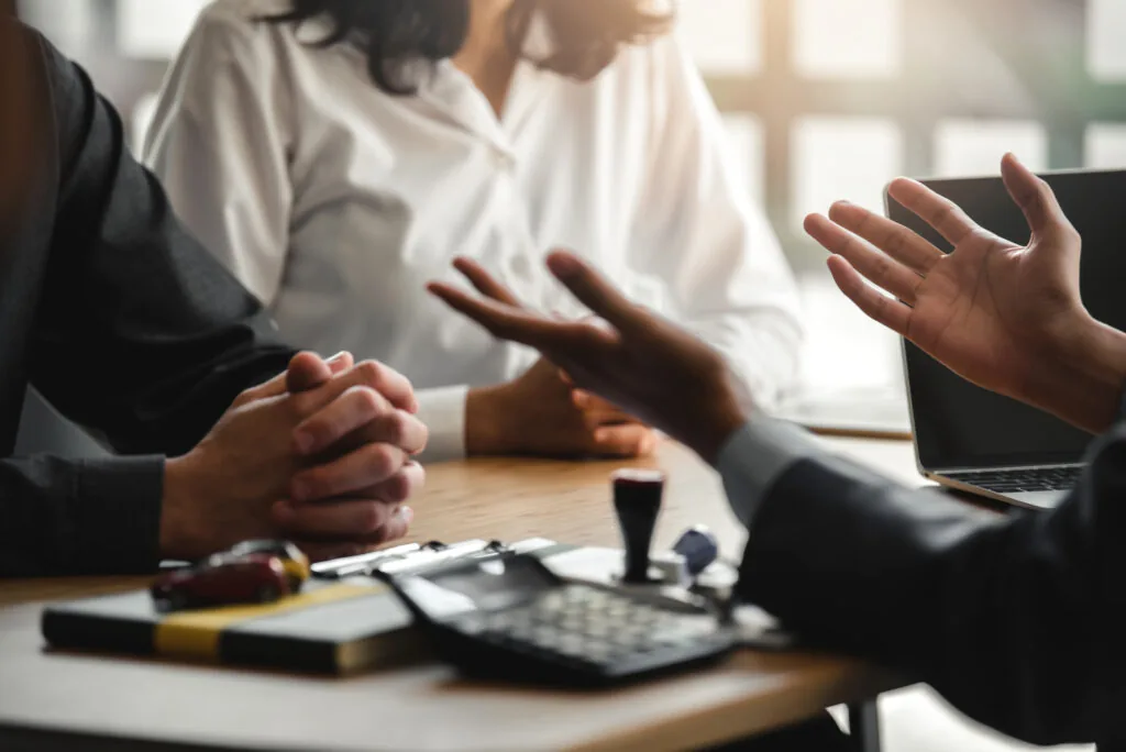 Investment broker or bank worker in suit consulting young couple in office.