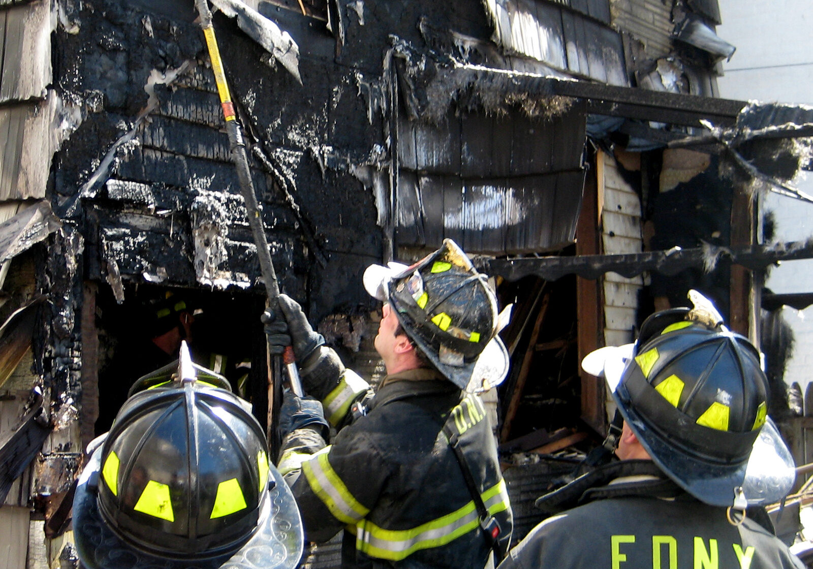 Fireman Using a Hook Fireman opens up the siding of a house after a fire